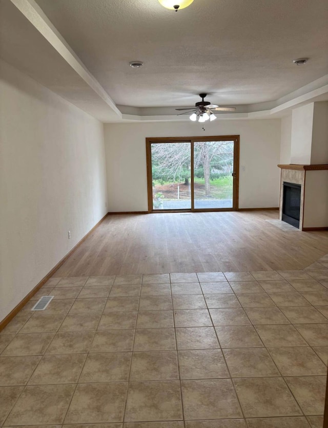 1432 Tall Grass, Hudson, WI 54016 - unfurnished living room featuring a ceiling fan, a raised ceiling, a tile fireplace, and baseboards