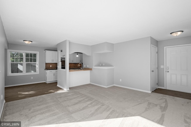 230 8th St NW, Elk River, MN 55330 - unfurnished living room featuring carpet floors, arched walkways, baseboards, and a sink