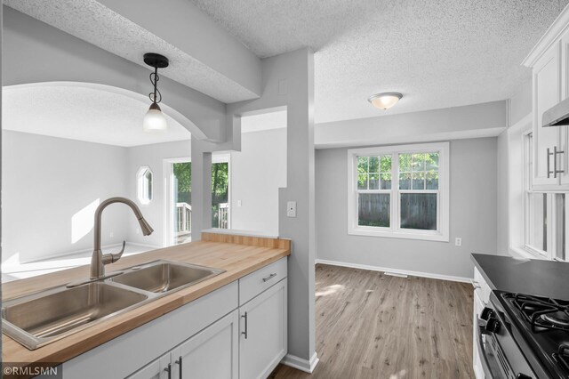 230 8th St NW, Elk River, MN 55330 - kitchen with a sink, wood counters, a textured ceiling, white cabinetry, and light wood finished floors
