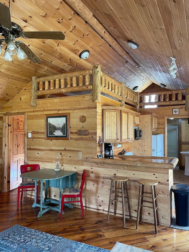 kitchen with wooden walls, freestanding refrigerator, a ceiling fan, wooden ceiling, and hardwood / wood-style flooring