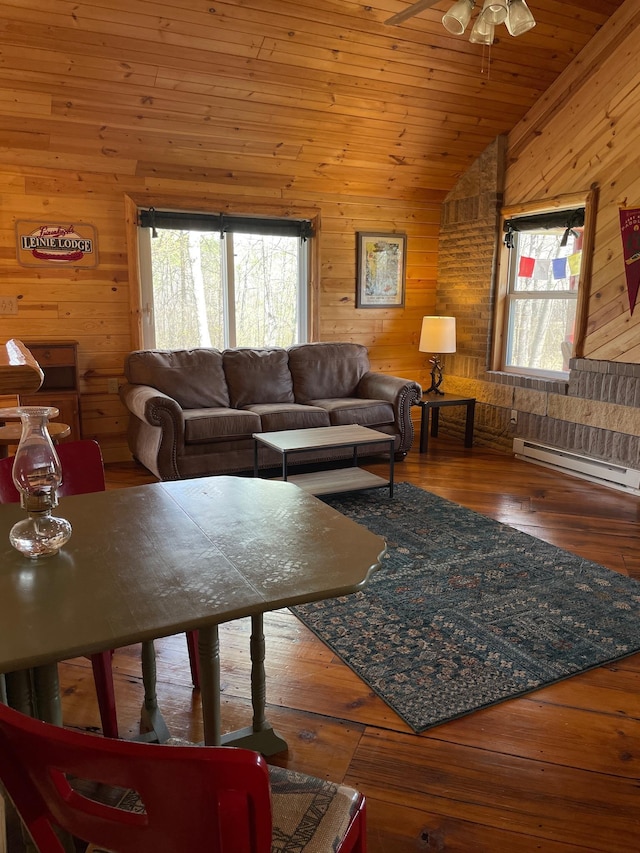 living area featuring wood walls, lofted ceiling, ceiling fan, a baseboard radiator, and wood-type flooring