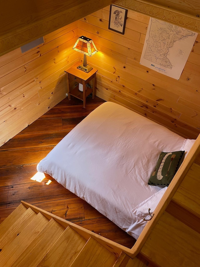 bedroom with wooden walls and wood finished floors