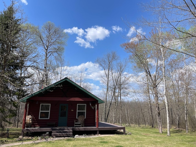 view of front facade with faux log siding, a front lawn, and a deck