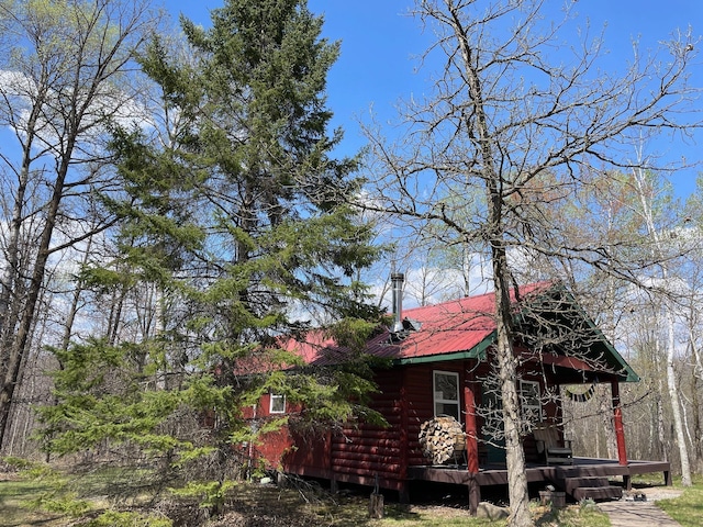 view of side of property featuring metal roof and a wooden deck