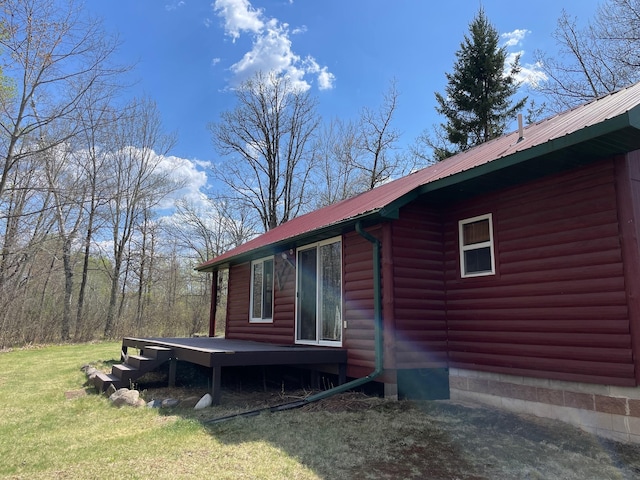 view of side of home featuring a wooden deck, metal roof, log veneer siding, and a lawn