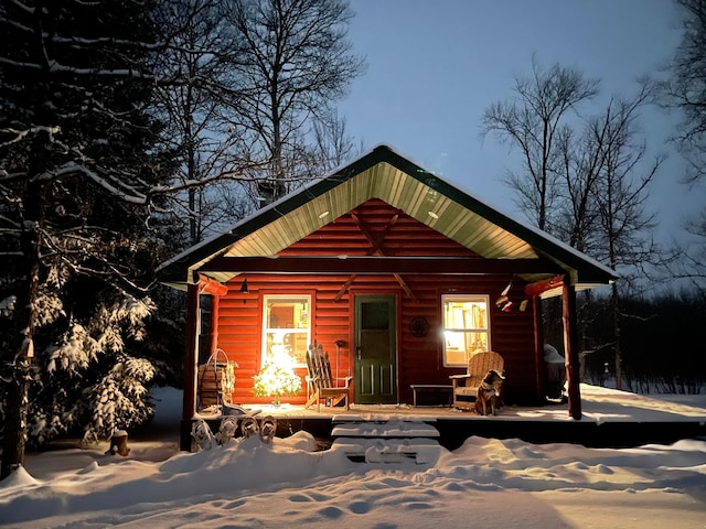 snow covered rear of property with covered porch