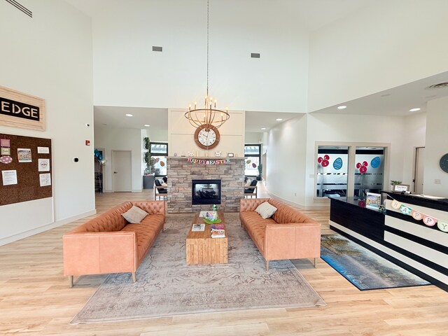 5173 Farnham Dr N, Hugo, MN 55038 - living area with a high ceiling, light wood-type flooring, a chandelier, a stone fireplace, and baseboards