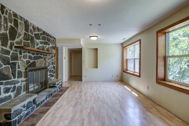 1286 Krattley Ln, North Hudson, WI 54016 - unfurnished living room with wood finished floors, a textured ceiling, and a stone fireplace