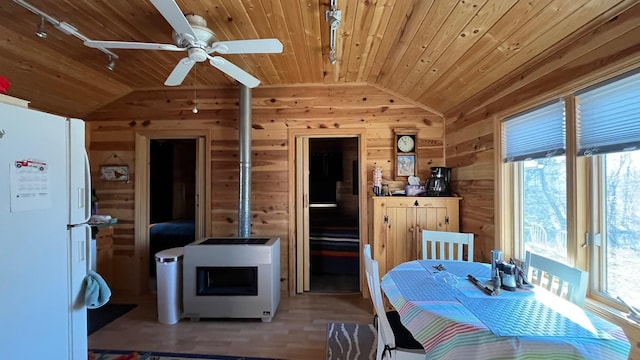 dining area featuring lofted ceiling, wooden ceiling, wooden walls, rail lighting, and a ceiling fan