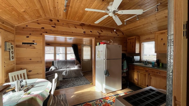 kitchen with lofted ceiling, freestanding refrigerator, wooden walls, wood ceiling, and ceiling fan