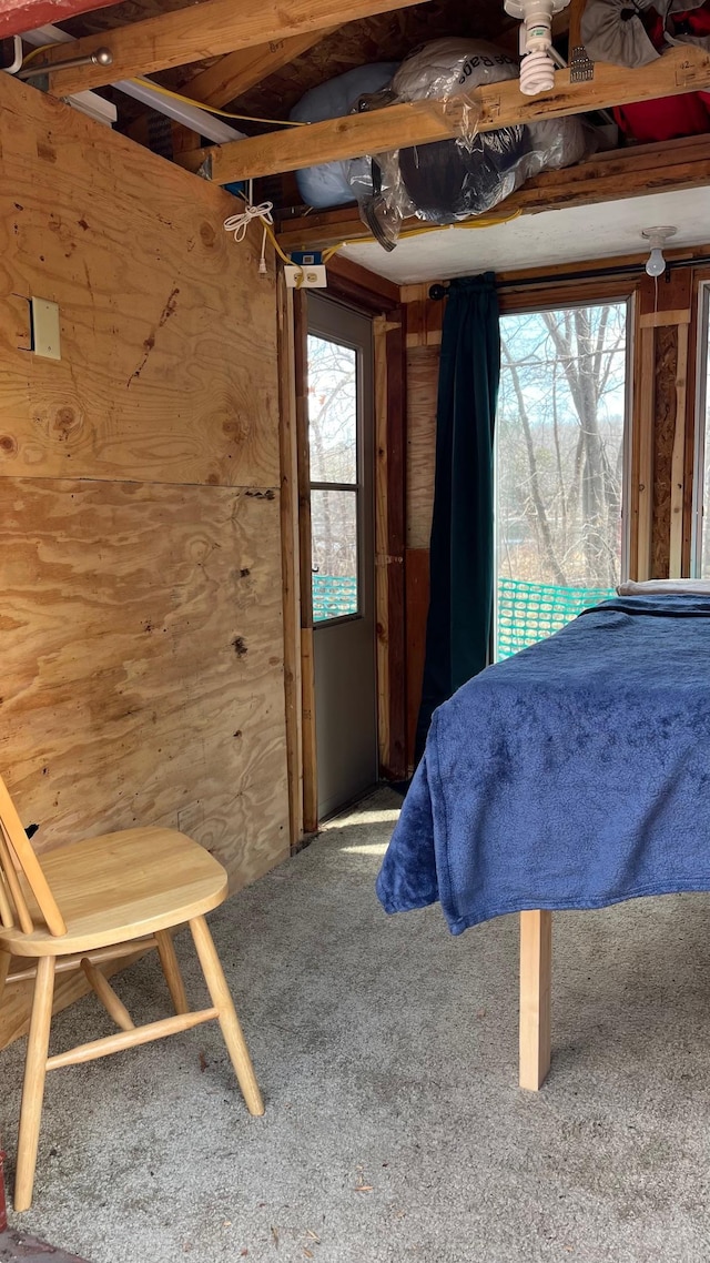 bedroom featuring carpet, wood walls, and access to outside