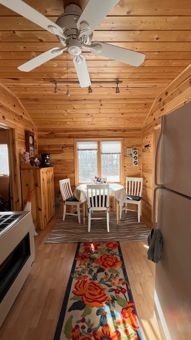 interior space featuring vaulted ceiling, wooden ceiling, ceiling fan, light wood-style floors, and wooden walls