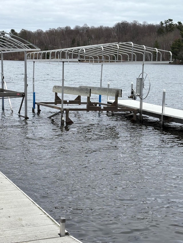 dock area featuring a water view, boat lift, and a wooded view