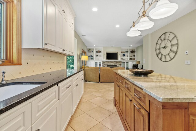 11600 43rd Ave N, Plymouth, MN 55442 - kitchen featuring dark stone countertops, backsplash, a stone fireplace, a sink, and hanging light fixtures