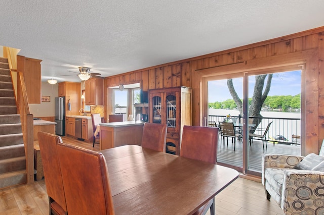 12177 Fremont Ln, Zimmerman, MN 55398 - dining area with wooden walls, stairs, a textured ceiling, light wood-style floors, and a ceiling fan