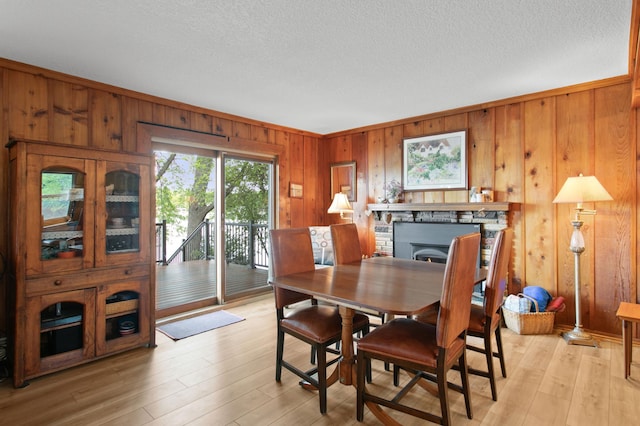 12177 Fremont Ln, Zimmerman, MN 55398 - dining space featuring wooden walls, light wood-style floors, a fireplace, and a textured ceiling