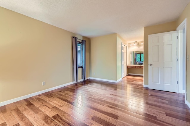 11476 65th Pl N, Maple Grove, MN 55369 - unfurnished room featuring hardwood / wood-style flooring, baseboards, track lighting, and a textured ceiling