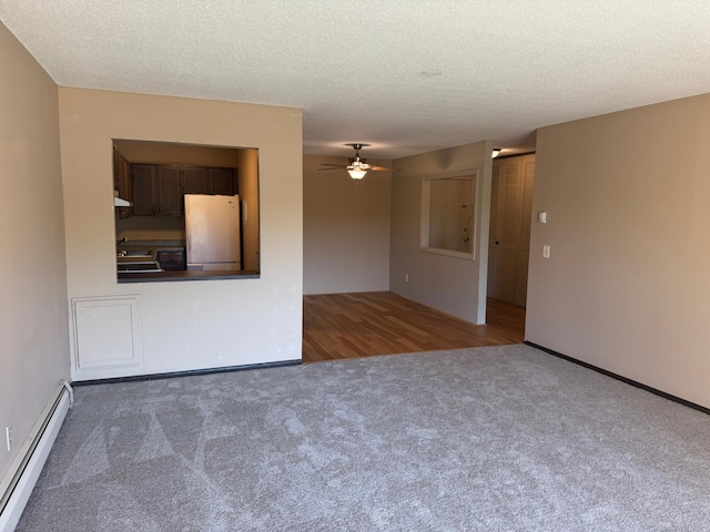 spare room featuring a baseboard radiator, carpet, ceiling fan, and a textured ceiling