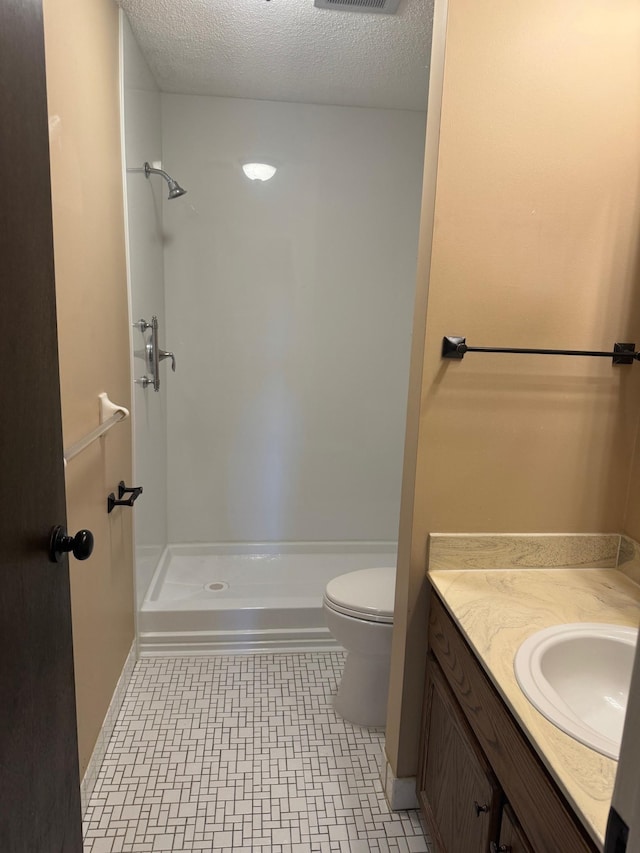 bathroom featuring a stall shower, toilet, vanity, and a textured ceiling