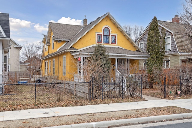 3205 Grand Ave S, Minneapolis, MN 55408 - view of front of property with a chimney, covered porch, a fenced front yard, roof with shingles, and stucco siding