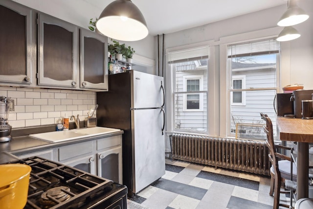 3205 Grand Ave S, Minneapolis, MN 55408 - kitchen with light floors, radiator, a sink, decorative backsplash, and freestanding refrigerator