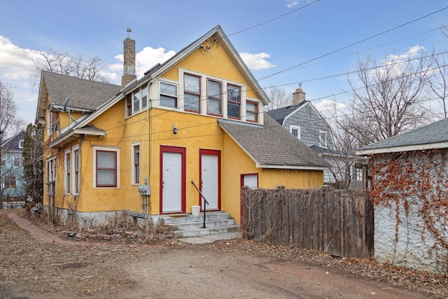 3205 Grand Ave S, Minneapolis, MN 55408 - view of front facade featuring a shingled roof, stucco siding, fence, and a chimney