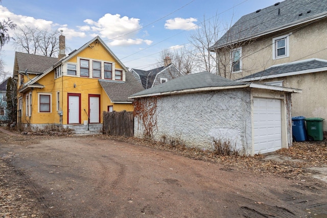 3205 Grand Ave S, Minneapolis, MN 55408 - back of property featuring stucco siding, roof with shingles, a garage, and a chimney