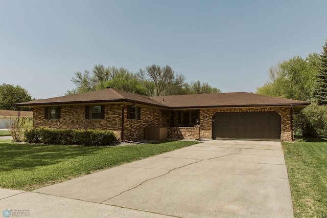 ranch-style house with a garage, a front lawn, driveway, and brick siding