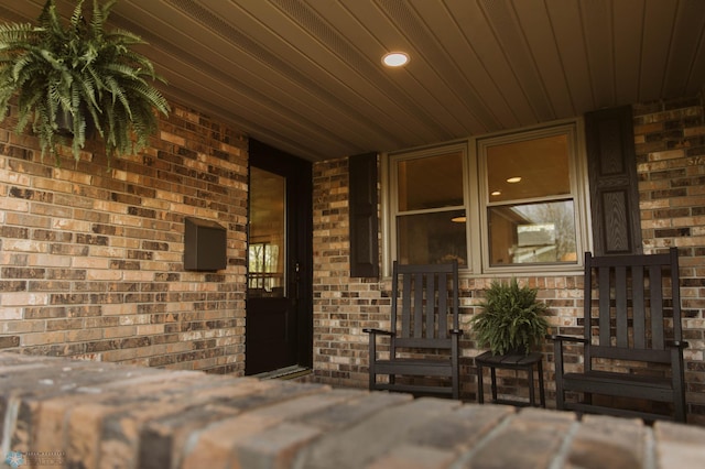 view of exterior entry with brick siding and a porch