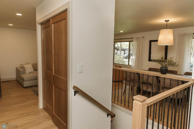 hallway featuring light wood finished floors, recessed lighting, plenty of natural light, and an upstairs landing
