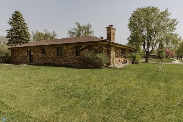 back of property with a chimney, a lawn, and brick siding