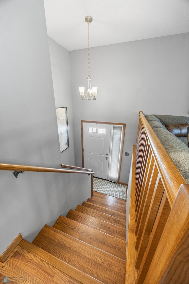 staircase featuring a chandelier and wood finished floors