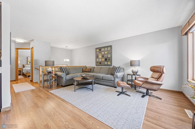 living area with light wood finished floors, a chandelier, and baseboards