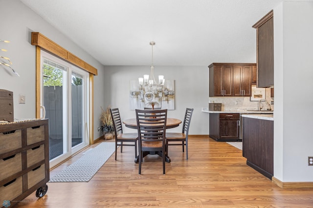 dining space featuring light wood-style floors, a chandelier, and baseboards