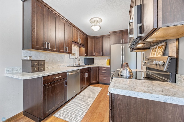 kitchen featuring stainless steel appliances, light wood-style floors, backsplash, light countertops, and dark brown cabinetry