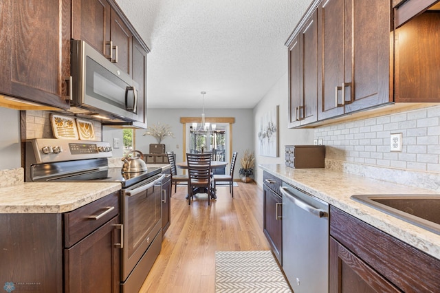 kitchen featuring appliances with stainless steel finishes, light countertops, decorative backsplash, light wood-style floors, and dark brown cabinets
