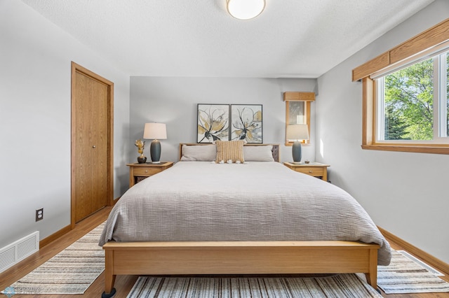 bedroom with wood finished floors, baseboards, and a textured ceiling