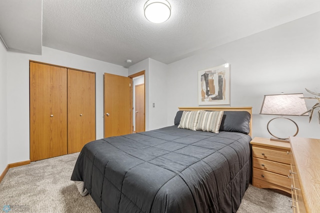 bedroom with light carpet, a closet, a textured ceiling, and baseboards