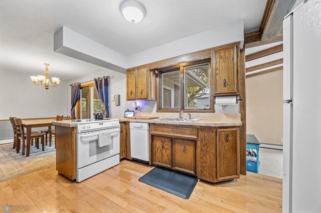 3105 Edgewood Dr N, Fargo, ND 58102 - kitchen featuring white appliances, a sink, a chandelier, light wood finished floors, and a peninsula