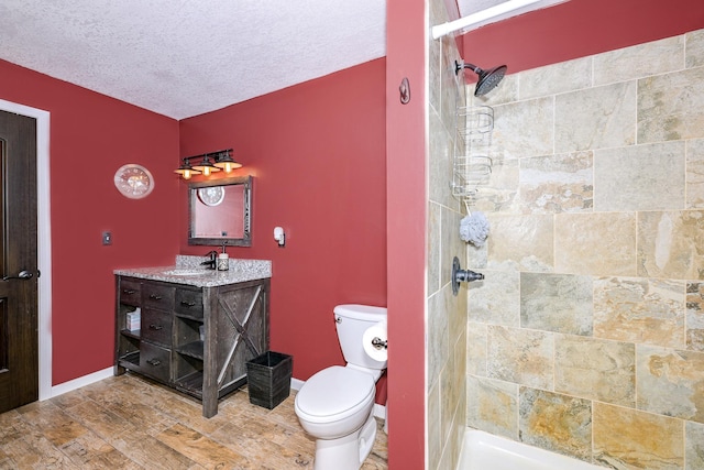 3818 Erickson Rd, Barnum, MN 55707 - bathroom featuring toilet, a tile shower, a textured ceiling, vanity, and baseboards