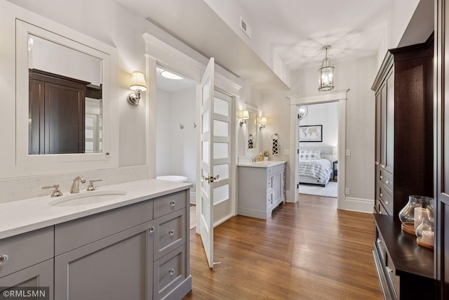 46 Crocus Pl, Saint Paul, MN 55102 - full bathroom with wood finished floors, ensuite bathroom, two vanities, baseboards, and a chandelier
