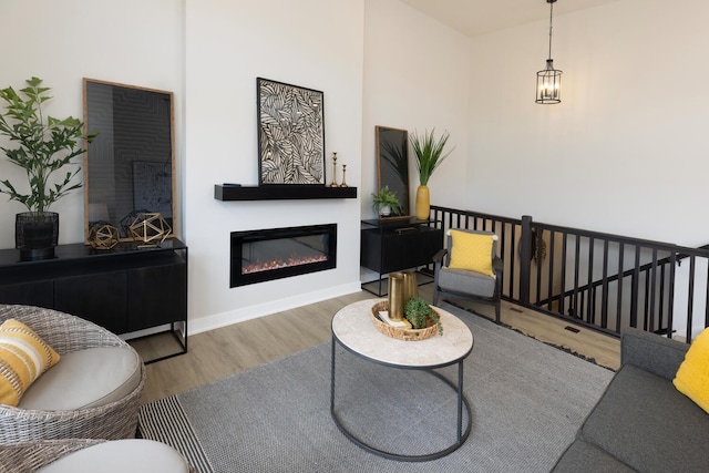 living area featuring wood finished floors, a glass covered fireplace, and baseboards