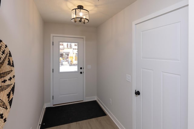 doorway featuring wood finished floors and baseboards