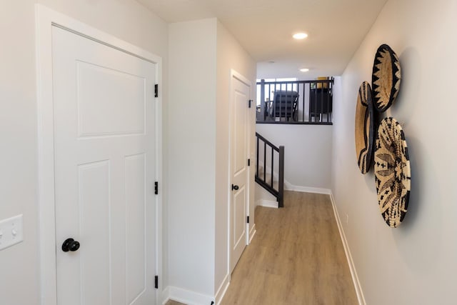 hallway with light wood-type flooring, baseboards, and recessed lighting