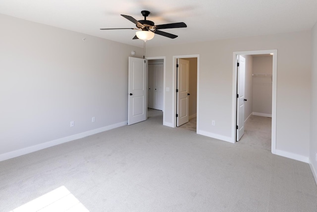 unfurnished bedroom featuring a spacious closet, light colored carpet, and baseboards