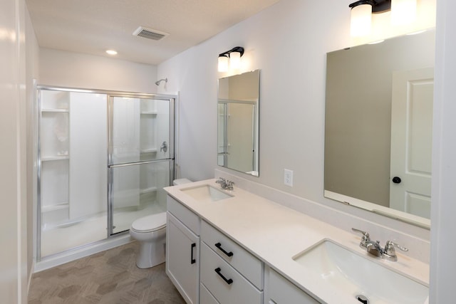 bathroom with a shower stall, toilet, double vanity, and recessed lighting