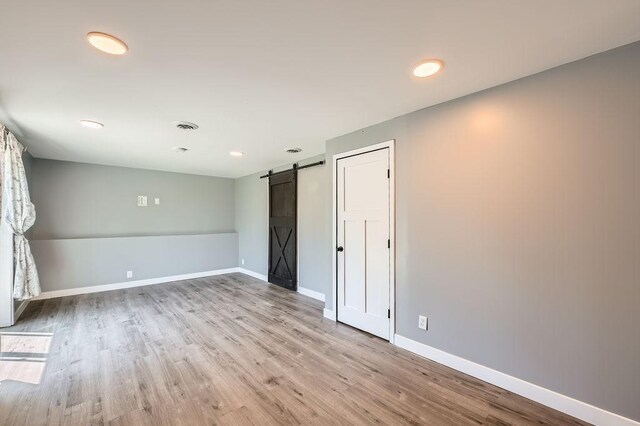 10034 191st Ave NW, Elk River, MN 55330 - unfurnished bedroom with a barn door, wood finished floors, baseboards, and recessed lighting