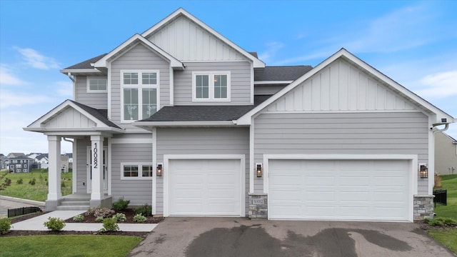 10082 Arrowwood Trl, Woodbury, MN 55129 - view of front of house with board and batten siding, a shingled roof, driveway, stone siding, and an attached garage