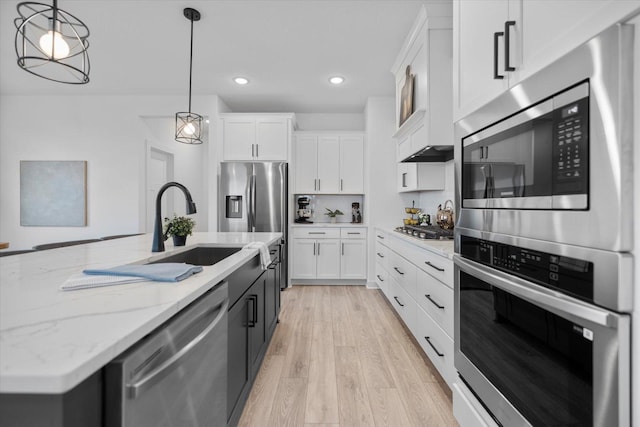 10082 Arrowwood Trl, Woodbury, MN 55129 - kitchen featuring appliances with stainless steel finishes, light wood-type flooring, white cabinetry, light stone counters, and hanging light fixtures