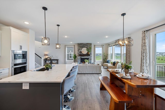 10082 Arrowwood Trl, Woodbury, MN 55129 - kitchen featuring appliances with stainless steel finishes, wood finished floors, a center island with sink, plenty of natural light, and recessed lighting